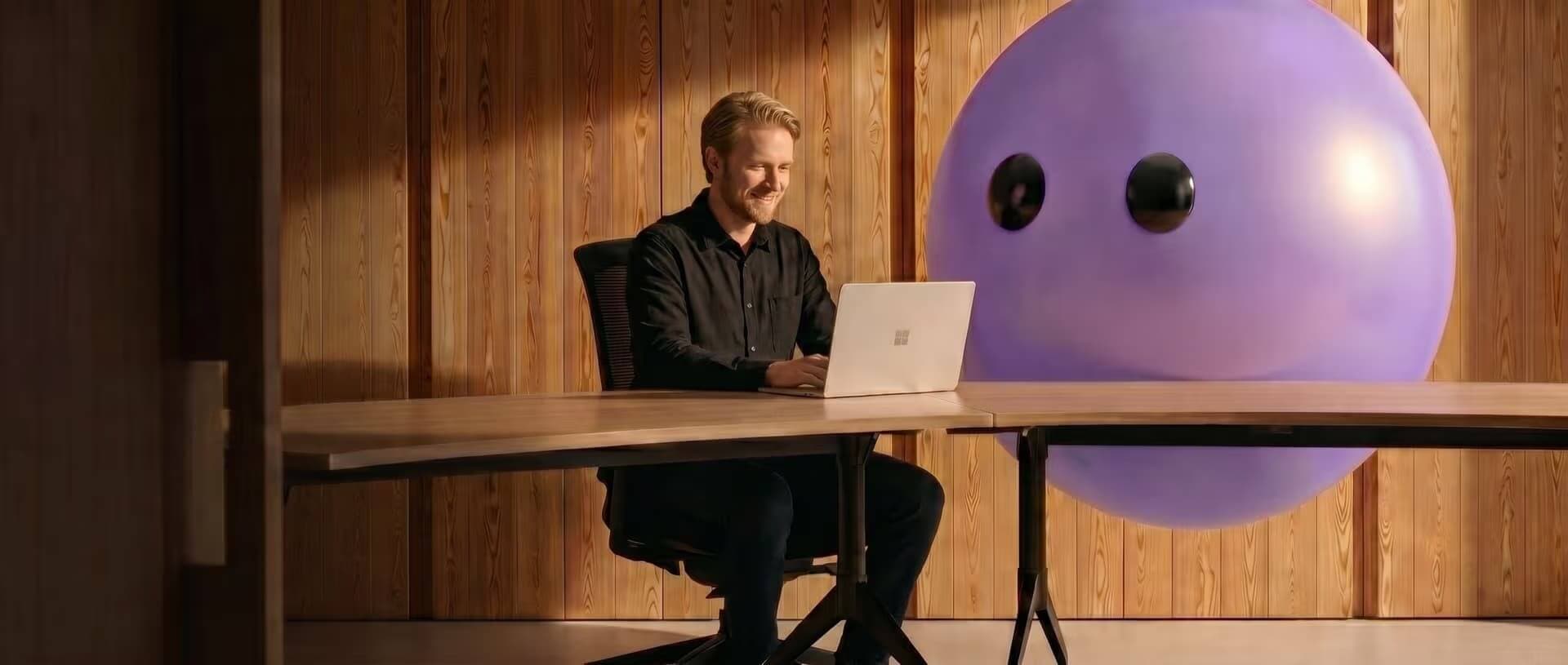 A support agent working at a laptop beside the purple Ayro mascot