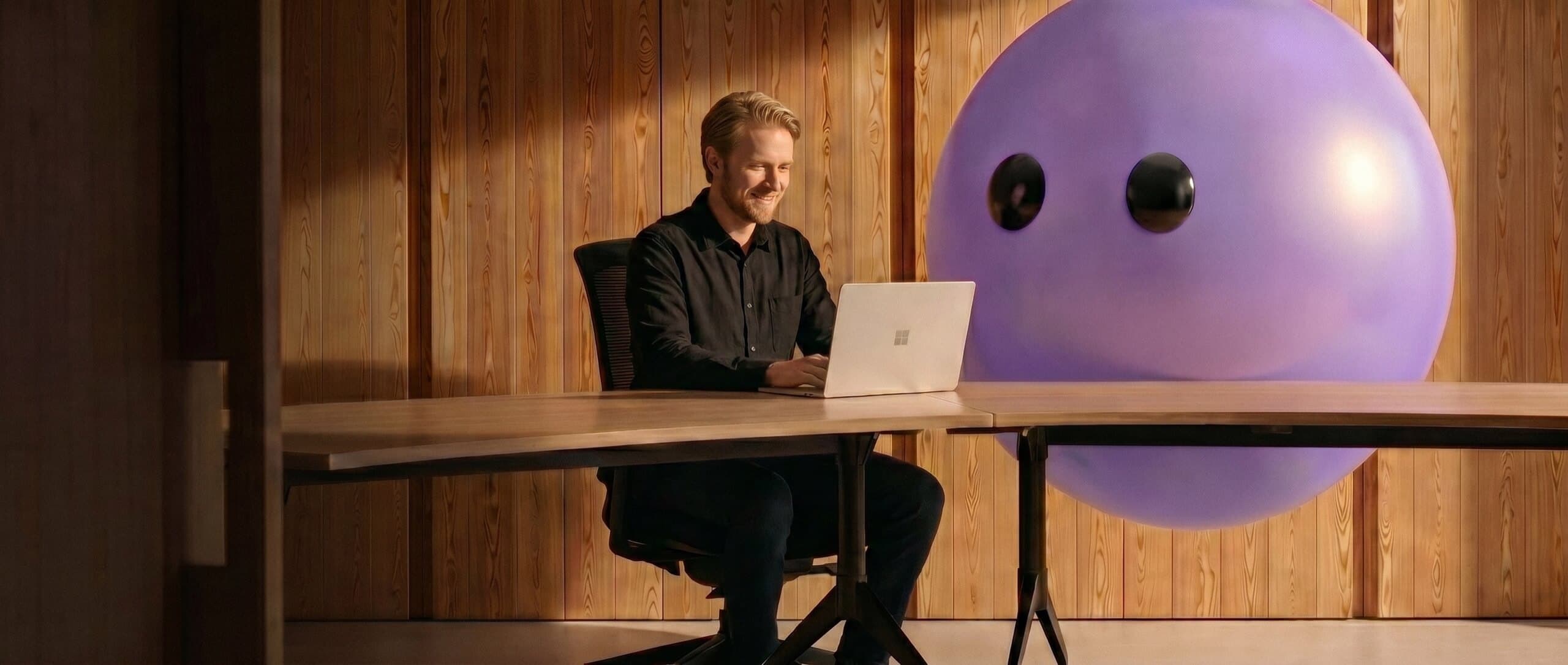 Support agent working at a laptop next to the Ayro mascot
